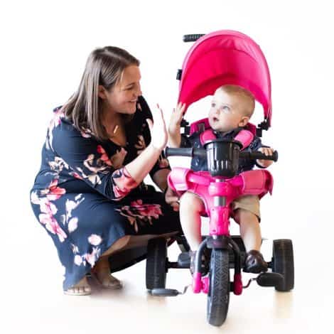 4-in-1 Joovy Tricycoo with wide tire, adjustable handle, safety harness, washable seat pad, and retractable canopy, in pink.