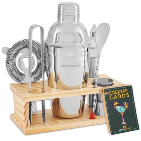 Silver cocktail shaker set with recipe cards, bar accessories, and a stylish pine wood stand. Perfect for mixology!